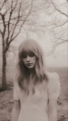 a woman with long hair standing in front of trees