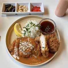 a white plate topped with food next to two bowls of sauce and condiments