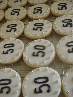 decorated cookies with black numbers and pearls on a cooling rack