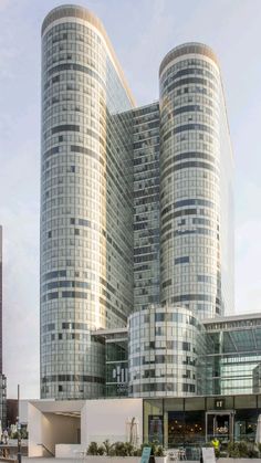 two very tall buildings sitting next to each other in front of a building with many windows