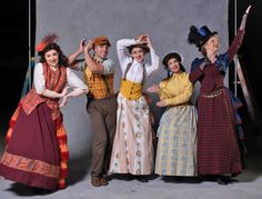 five people dressed in period clothing posing for a photo with their hands on their head