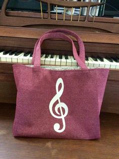 a purple bag with a white treble on it sitting next to a piano keyboard