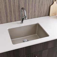 a kitchen sink sitting on top of a counter next to a cutting board and knife