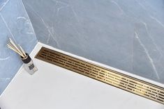 a white toilet with gold trim and two bamboo sticks sticking out of the drain cover