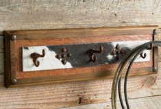 a cowhide coat rack with four hooks and two rope hangers on the wall