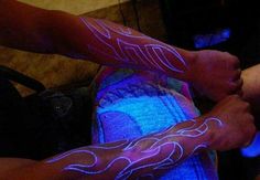 two people with glow tattoos on their arms and legs, one holding the other's hand