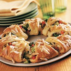 a plate topped with pastry covered in toppings on top of a wooden table next to plates