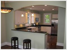 a kitchen with two bar stools next to an island in the middle of it