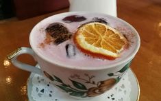 a cup filled with liquid and topped with an orange slice on top of a saucer