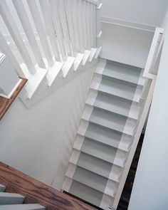 an overhead view of a stair case with white railings and wooden steps leading up to the second floor