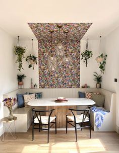 a dining room table with two chairs and a bench in front of a painting on the wall