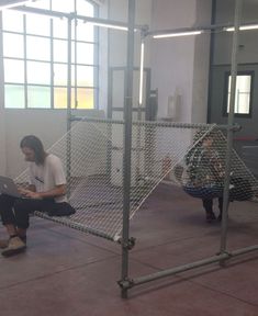 two people sitting on the ground in front of a metal cage with a laptop computer