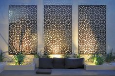 an outdoor seating area is lit up with lights and decorative screens on the wall behind it