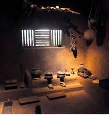 a dimly lit room with several pots and bowls on the floor, in front of a window