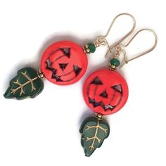 "Classic Jack O Lantern earrings for Halloween.  Carved, orange howlite pumpkins are matched with pressed-glass green leaves and crystal accents.  Petaled 22K gold plated findings fit the autumnal, botanical scene.  Spooktacular! Quality 14K gold-filled ear wires - choose from kidney or French.  14K gold-filled head pins.  Length is 2\". All my Etsy jewelry offerings are designed and created by me. As an independent craftsperson, I value your patronage. Please use coupon code 10OFF2 at checkout Jack O Lantern Earrings, Handmade Green Halloween Earrings, Green Earrings For Halloween Gift, Green Halloween Dangle Earrings, Green Novelty Jewelry For Halloween, Classic Jack O Lantern, Orange Jack O Lantern, Thanksgiving Earrings, Spooky Halloween Gifts