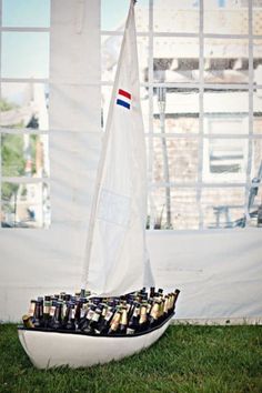 a sailboat filled with beer bottles sitting in the grass