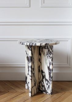 a marble table sitting on top of a hard wood floor next to a white wall