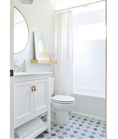 a white toilet sitting next to a bath tub in a bathroom under a mirror above a sink