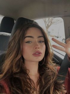 a woman sitting in the back seat of a car with her hand up to her face