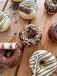 there are many different donuts on the wooden table, including one with chocolate frosting and sprinkles