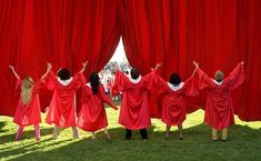 some people are standing in front of red curtains with their hands up and arms out