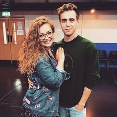 a man and woman standing next to each other in a room with wooden flooring