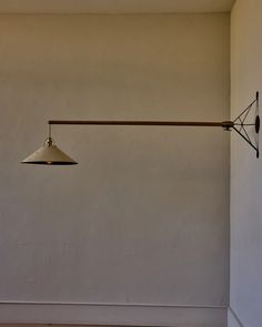 a lamp hanging from the side of a white wall next to a wooden flooring