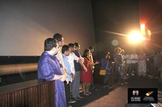 a group of people standing in a room with a projector screen and lights on