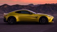 a yellow sports car is parked in front of some mountains at sunset with the sun going down