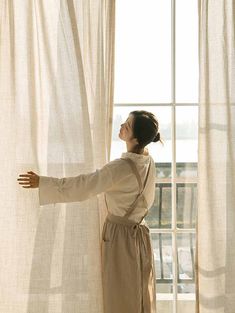 a woman standing in front of a window with her arms stretched out to the side