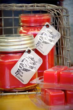 some red candles are sitting on a table with tags hanging from the top of them