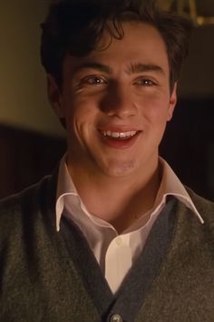 a young man smiling at the camera in a dark room with light coming from behind him