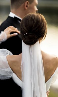 the bride and groom are dressed in black tuxedo with white veils on their heads