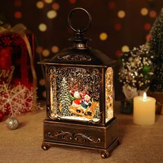 a lighted lantern with santa claus and reindeer on it next to christmas trees, candles and presents