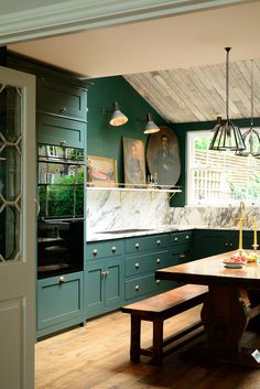 a kitchen with green cabinets and marble counter tops, along with wooden benches in the center