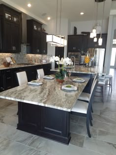 a large kitchen with marble counter tops and black cabinets