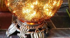 an ornate glass bowl sitting on top of a metal stand next to flowers and candles