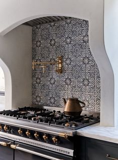 a stove top oven sitting inside of a kitchen next to a wall covered in blue and white tiles