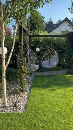 two hanging chairs in the middle of a garden