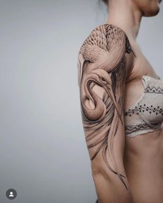 a woman's arm and shoulder with an artistic tattoo design on the left side