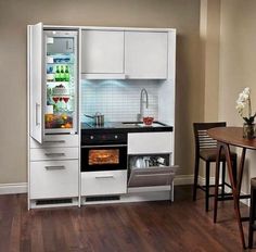 an open refrigerator in the corner of a kitchen next to a dining table and chairs