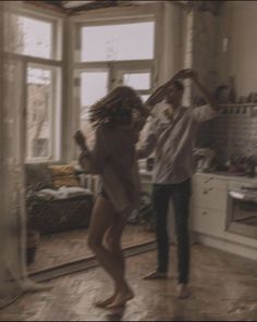 two people standing in a room with open windows