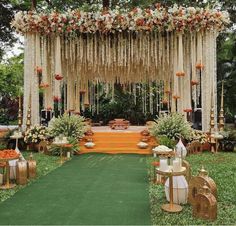 an outdoor wedding setup with orange and white flowers on the altar, greenery and chairs