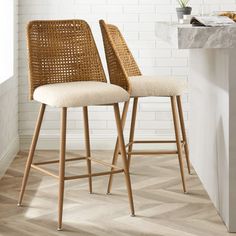 two wicker barstools in front of a white brick wall and wooden floor