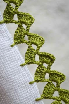 crochet stitches on the side of a piece of white fabric with green thread