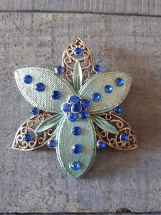 "Lovely vintage floral filigree brooch. Silver tone metal with bright blue rhinestones. 3 etched metal floral petals and 3 filigree leaves make this a beautifully designed brooch. Measures 2.5\" x 2.75\"." Ornate Blue Brooches For Wedding, Ornate Blue Wedding Brooches, Floral Filigree, Metal Etching, Blue Rhinestones, Bright Blue, Vintage Silver, Vintage Floral, Brooch Pin