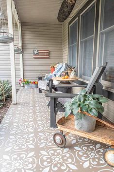 a porch with a potted plant on top of a wooden cart next to a window