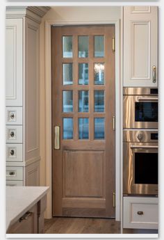 a kitchen with an oven, microwave and wooden door