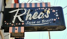 a sign that says rhees salon of beauty hanging from the side of a building