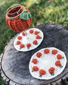 two crocheted coasters sitting on top of a tree stump next to a cup